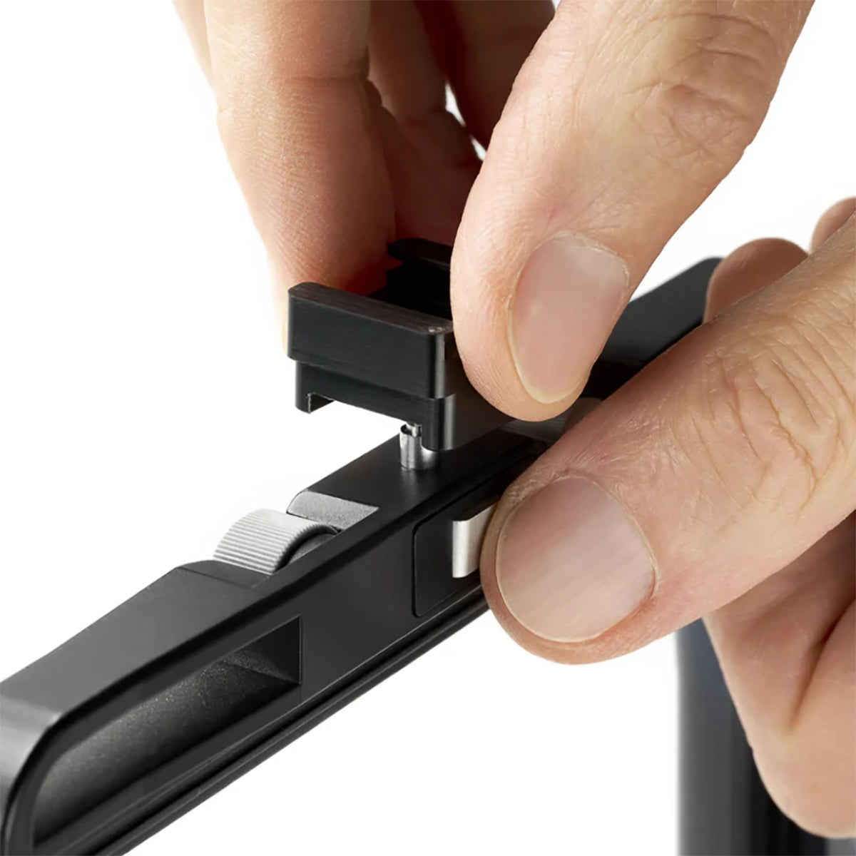 Close-up of hands installing an Arca-Swiss cold shoe to the top of an F-line camera format frame.